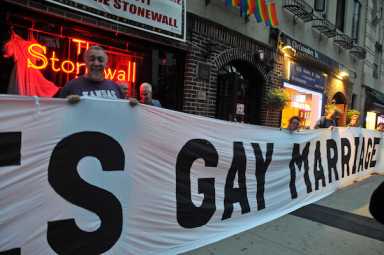 Activists stand outside the Stonewall Inn to celebrate the passage of the Marriage Equality NY bill.
