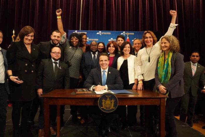 Former Governor Andrew Cuomo, flanked on the right by Lieutenant Governor Kathy Hochul, is joined by advocates as he signs GENDA and the ban on conversion therapy.