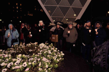 Vigil participants standing in the shadow of the NYC AIDS Memorial on World AIDS Day in 2019.
