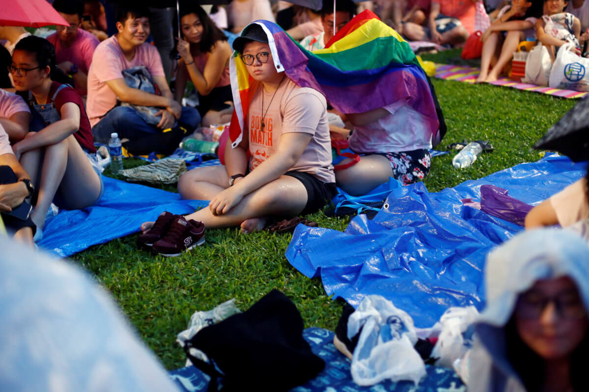 Participants of Pink Dot, an annual event organised in support of the LGBT community, shelter themselves from the rain with a gay pride flag at the Speakers’ Corner in Hong Lim Park in Singapore