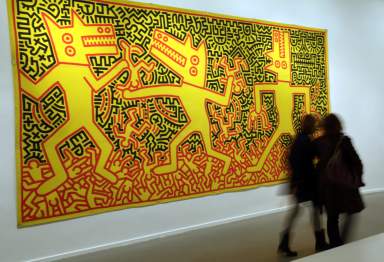 Visitors walk past an untitled art creation by American artist Haring (1958-1990) during his exhibition retrospective at the Musee d’Art Moderne in Paris