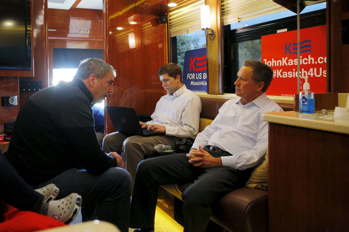 U.S. Republican presidential candidate and Ohio Governor John Kasich talks to chief strategist John Weaver on his campaign bus in Plymouth