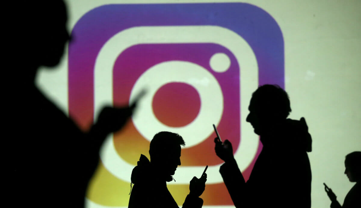 FILE PHOTO: Silhouettes of mobile users are seen next to a screen projection of Instagram logo in this picture illustration