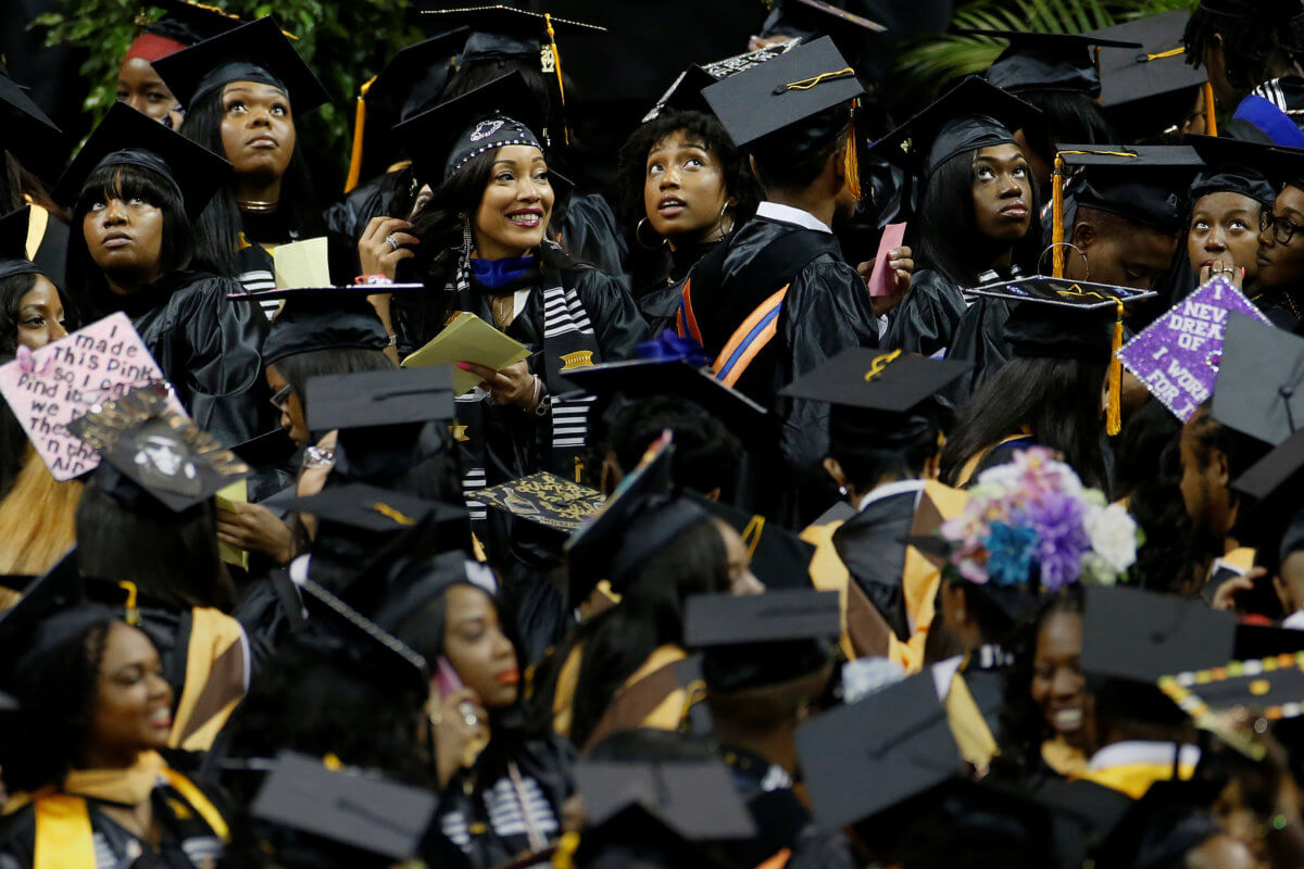 Gaduates look at the screen during a commencement for Medgar Evers College in the Brooklyn borough of New York City