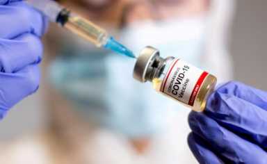 FILE PHOTO: A woman holds a medical syringe and a small bottle labelled “Coronavirus COVID-19 Vaccine
