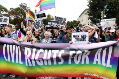 LGBTQ activists and supporters block the street outside the U.S. Supreme Court as it hears arguments in a major LGBT rights case in Washington