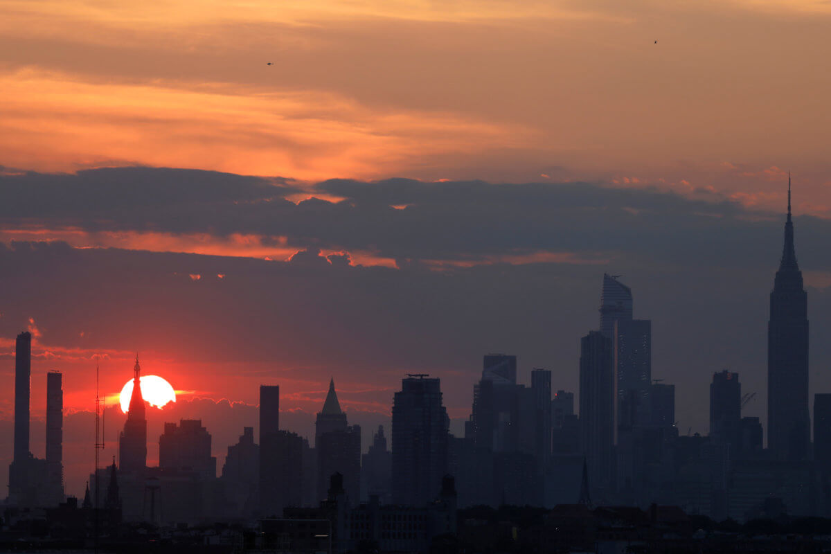 Sunset is seen behind the skyline of Manhattan on the 4th of July in New York City