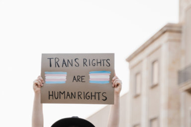 Trans woman at gay pride protest holding transgender flag banner – Lgbt celebration event concept