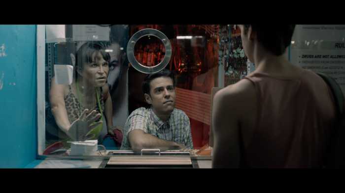 Three people stand at a booth in a scene of “Phantom of the Sauna”