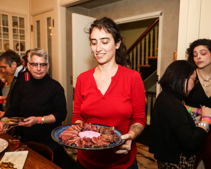Alex Koones, founder and organizer of Babetown, serving a plate of seared heart with purple horseradish cream at the Valentine’s Day event, Babetown Cruising, before the pandemic in 2020.