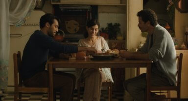 Three people sit at a table in a scene from "The Blue Caftan."
