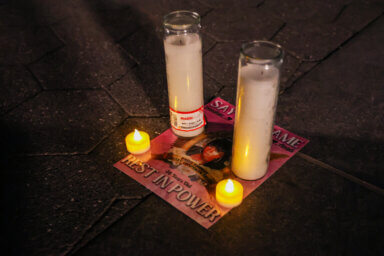 Candles cover a flyer paying tribute to