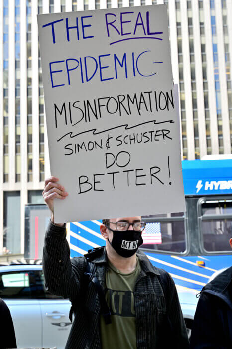 Brandon Cuicchi holds a sign outside Simon & Schuster's headquarters.