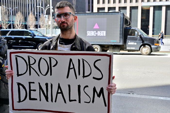 Activist Jason Rosenberg holds up a sign outlining ACT UP's core demand to Simon & Schuster.