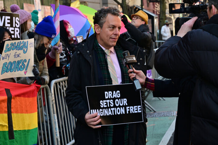 Assemblymember Tony Simone of Manhattan holds a sign during an interview.