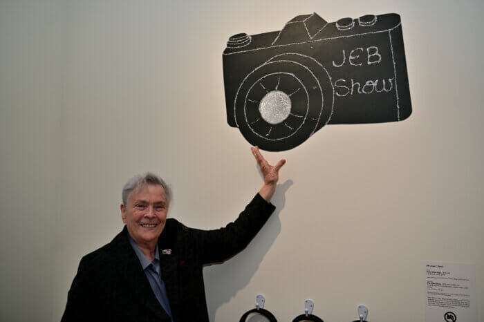 "JEB" Joan E. Biren smiles with a camera.
