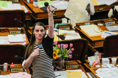 State Rep. Zooey Zephyr, D-Missoula, alone on the house floor stands in protest as demonstrators are arrested in the house gallery, Monday, April 24, 2023, in the Montana State Capitol in Helena, Mont.