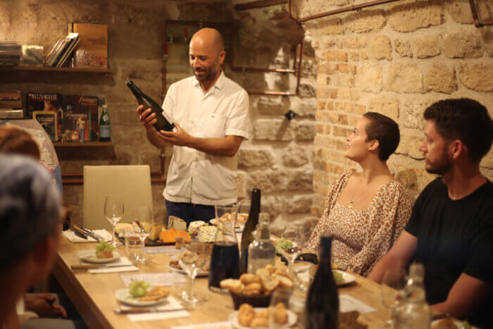 WeTasteParis owner, French chef, and tour guide Andrés Medrano prepares to serve guests a bottle of wine for a meal during a tour.