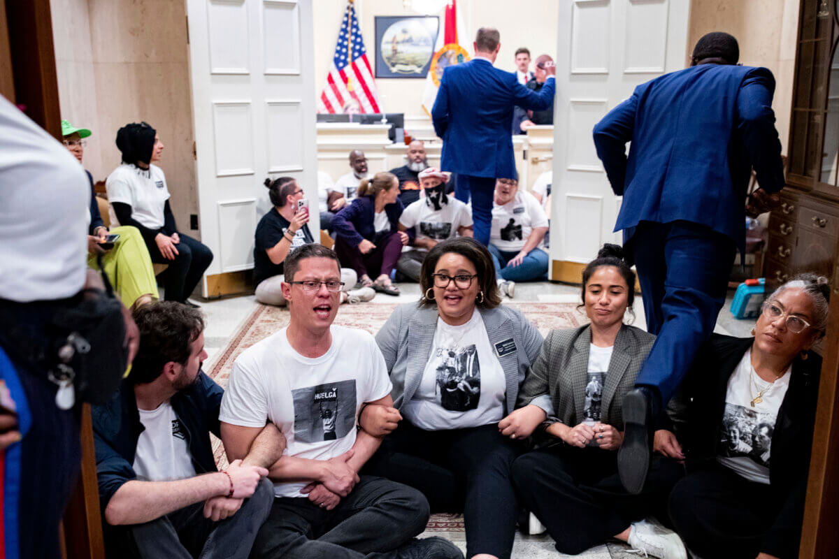 Dozens of activists stage a sit-in outside Florida Gov. Ron DeSantis' office and force people to step over them to reach DeSantis' office as they speak out against the governor and his policies, Wednesday, May 3, 2023, in Tallahassee, Fla.