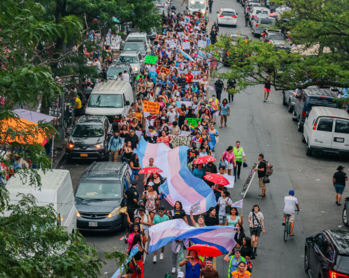 Multiple large-scale Trans Flags are carried through the TransLatinx March.