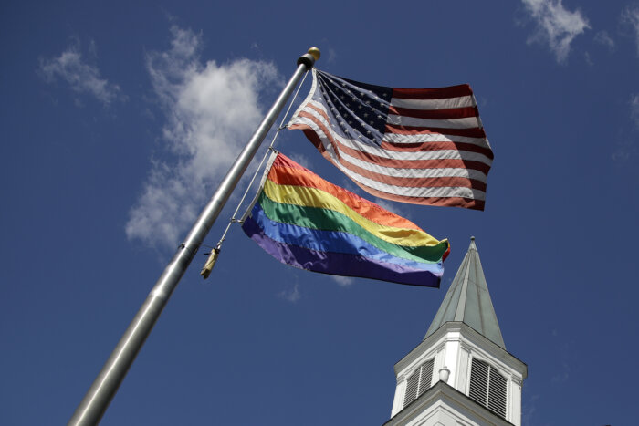 A Rainbow Flag flies with the US flag in front of the Asbury United Methodist Church in Prairie Village, Kan., on Friday, April 19, 2019.