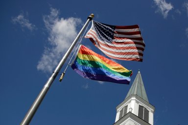 A Rainbow Flag flies with the US flag in front of the Asbury United Methodist Church in Prairie Village, Kan., on Friday, April 19, 2019.