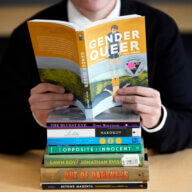 Amanda Darrow, director of youth, family and education programs at the Utah Pride Center, poses with books that have been the subject of complaints from parents on Dec. 16, 2021, in Salt Lake City.