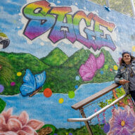 Artist Karen "KayLove" Pedrosa poses in front of the mural she painted for the SAGE Center in the Bronx.