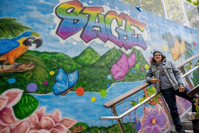 Artist Karen "KayLove" Pedrosa poses in front of the mural she painted for the SAGE Center in the Bronx.