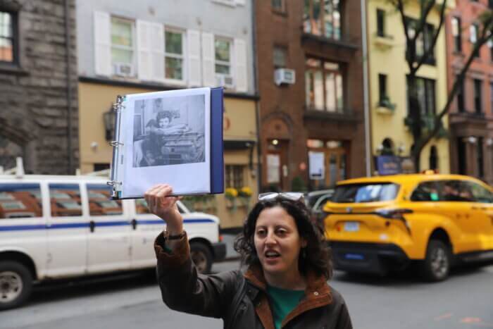 Amanda Davis holds up a photo of Lorraine Hansberry in front of her residence.
