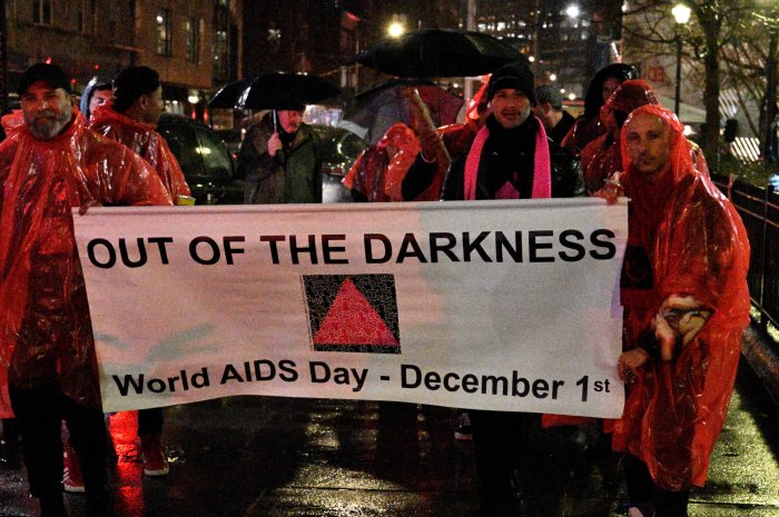 Advocates carry the banner at the 32nd Out of the Darkness World AIDS Day candlelight vigil in 2023.