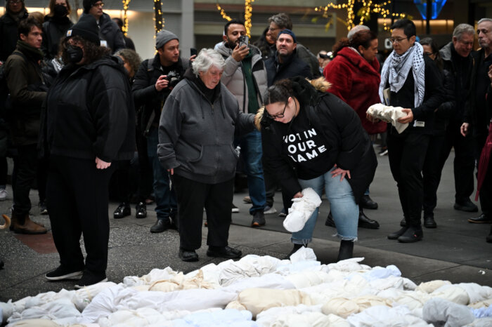 Organizer Leslie Cagan (middle, left) guides the process of laying effigies to rest.