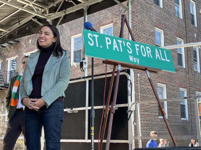 Congressmember Alexandria Ocasio-Cortez next to the sign marking the newly-renamed street in honor of St. Pat's for All.