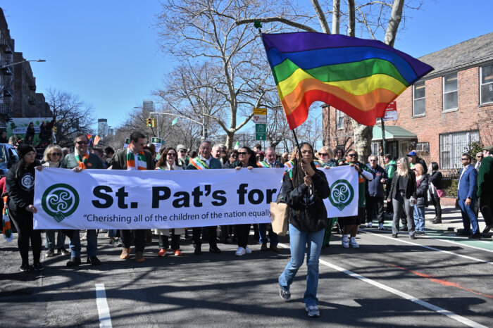 The St. Pat's for All banner, led by a Rainbow Flag, barrels along the parade route.