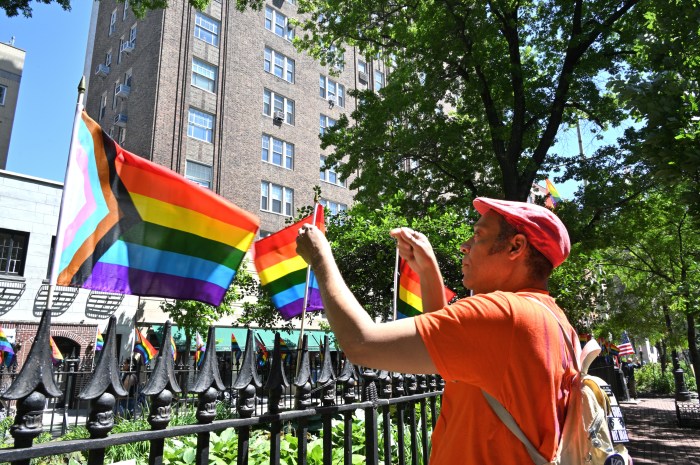 Jay W. Walker installs small Rainbow Flags on the wrought iron fence.