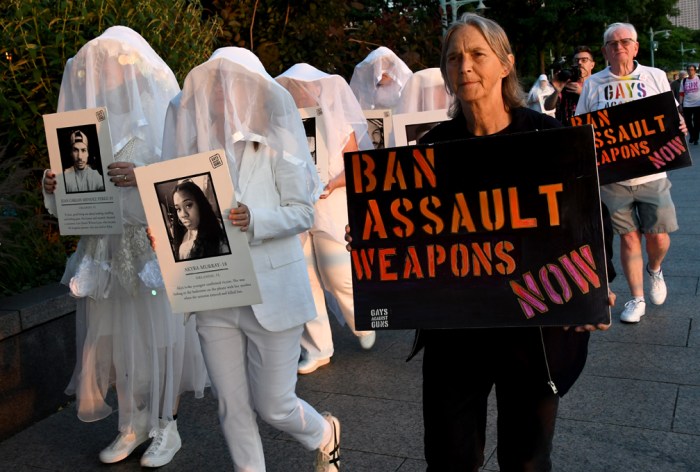 Humans walk alongside a message condemning assault weapons.