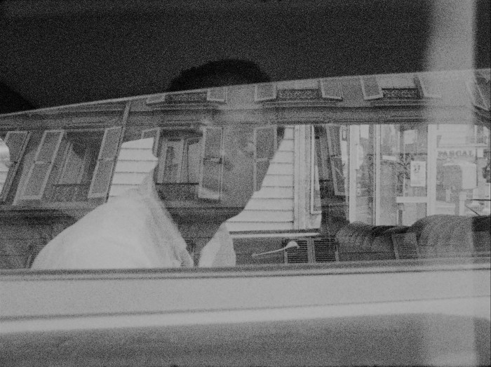 A man looks out of the window while sitting in a car in a black and white photo.