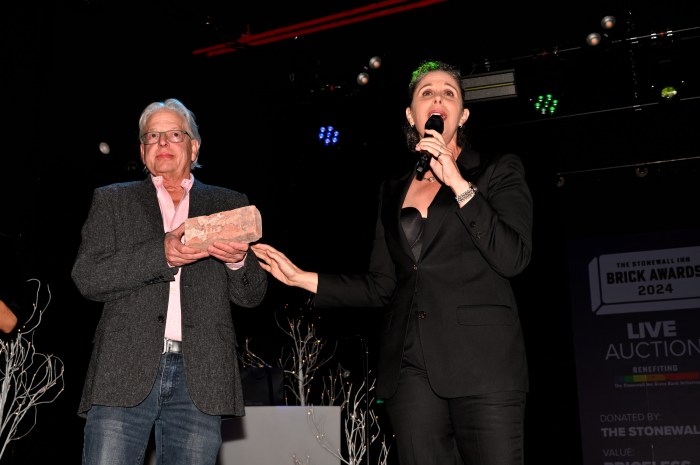 Stonewall Inn co-owner Kurt Kelly holds an original Stonewall Inn brick alongside auctioneer Dana Goldberg.