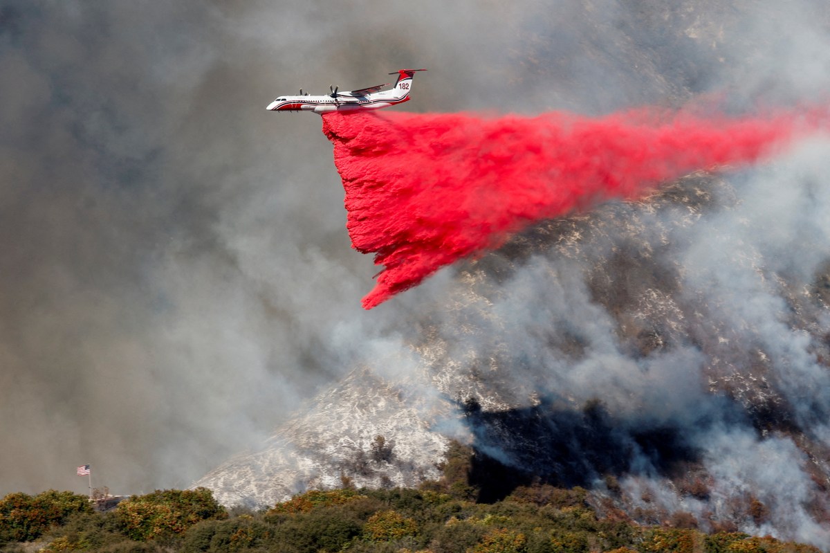 A plane makes a drop as smoke billows from the Palisades Fire at the Mandeville Canyon, in Los Angeles, California, U.S., January 11, 2025.