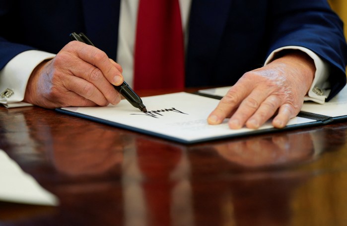 President Donald Trump signs executive orders in the Oval Office at the White House in Washington, U.S., January 30, 2025.