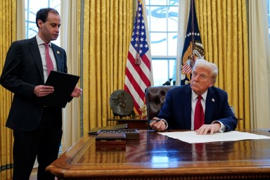 President Donald Trump signs executive orders as White House Staff Secretary Will Scharf stands by in the Oval Office at the White House in Washington, U.S., January 30, 2025.