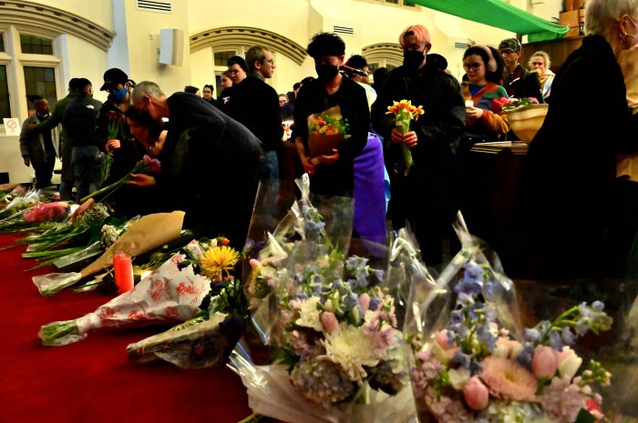 Community members lay flowers down in honor of Sam Nordquist.