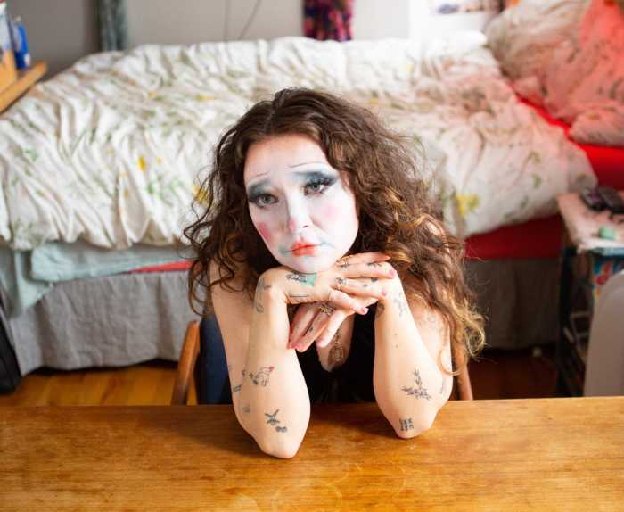 The artist Fielded poses for a photo while sitting at a table as part of the artist's latest music album cover.