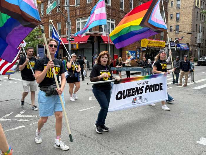 The lead banner proceeds along the parade route at Queens Pride.