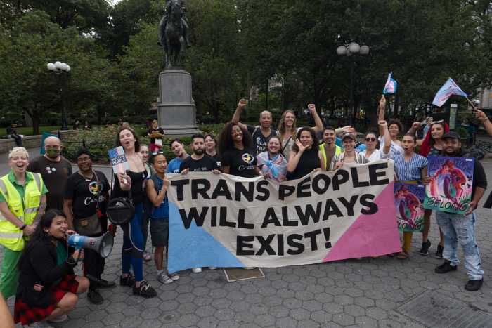 Advocates huddle around the banner at Washington Square Park.