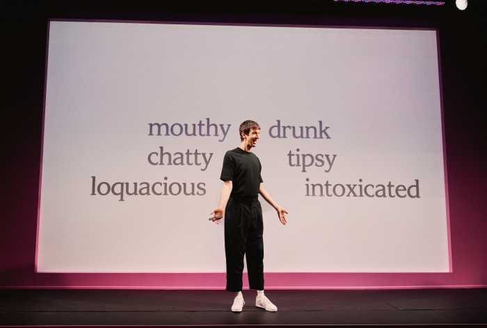 The PowerPoint slides display, in black and white, every word of his manic monologue