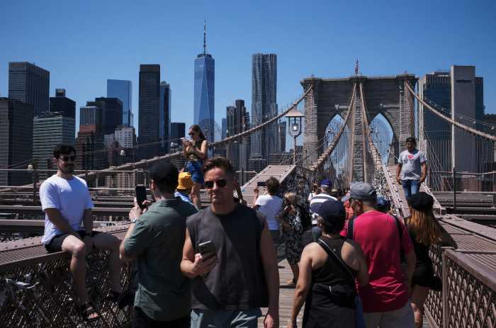 People walk across the Brooklyn Bridge in New York City on Aug. 8, 2025.