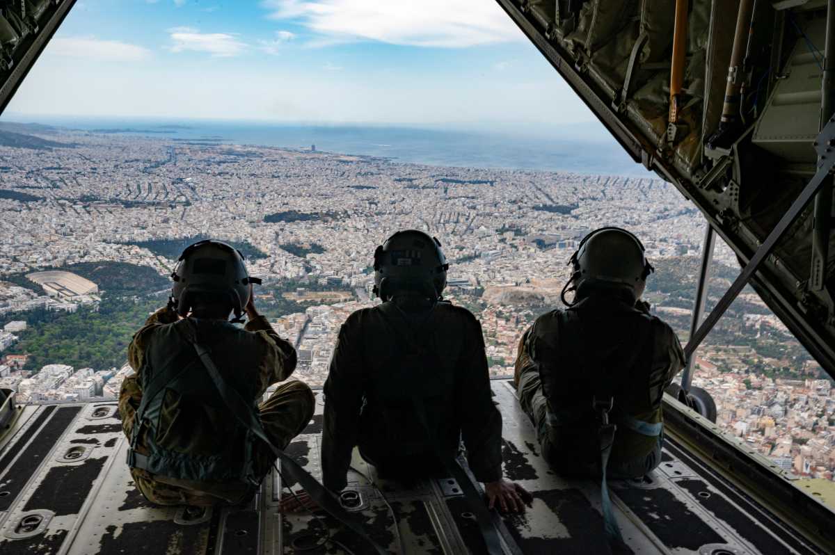 Two US Air Force members and a Hellenic air force member ramp surf on a C-130J Super Hercules over Athens, Greece, during an exercise on May 2, 2025.