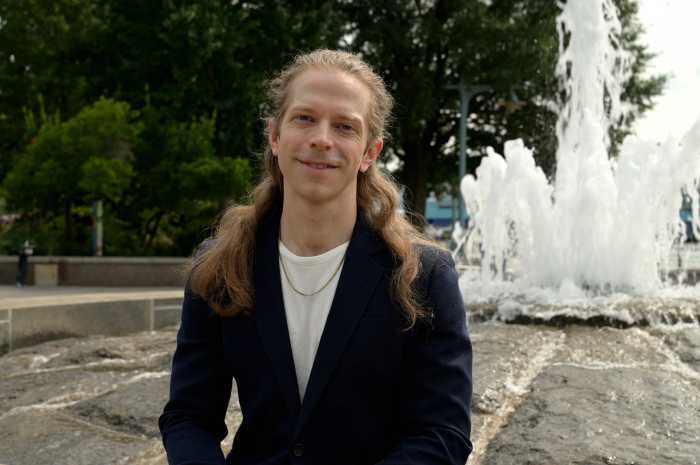 David Bloom smiles while sitting in front of a fountain in Manhattan.