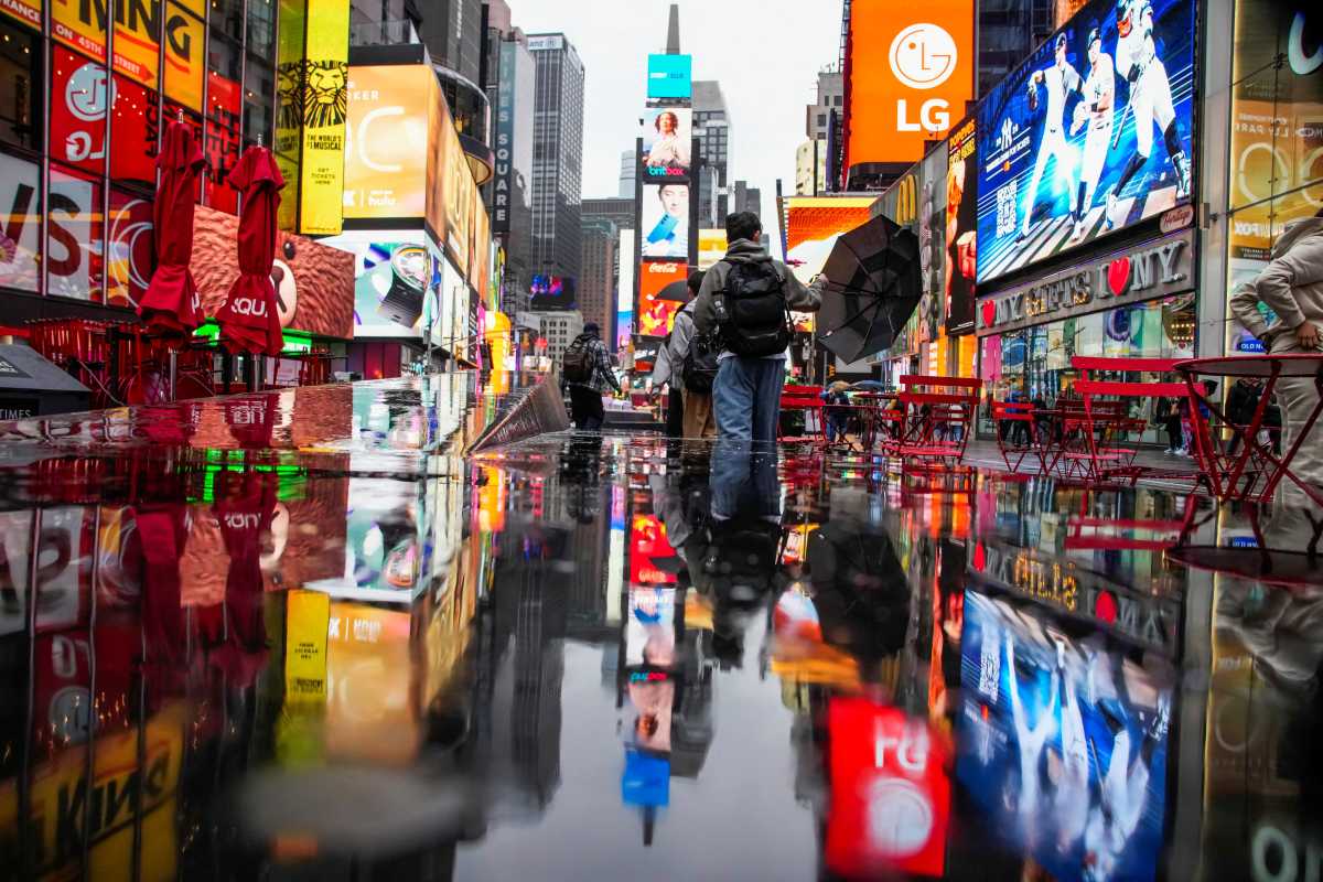 A person walks through wind and rain during a nor'easter storm at Times Square in New York City, U.S., October 13, 2025.